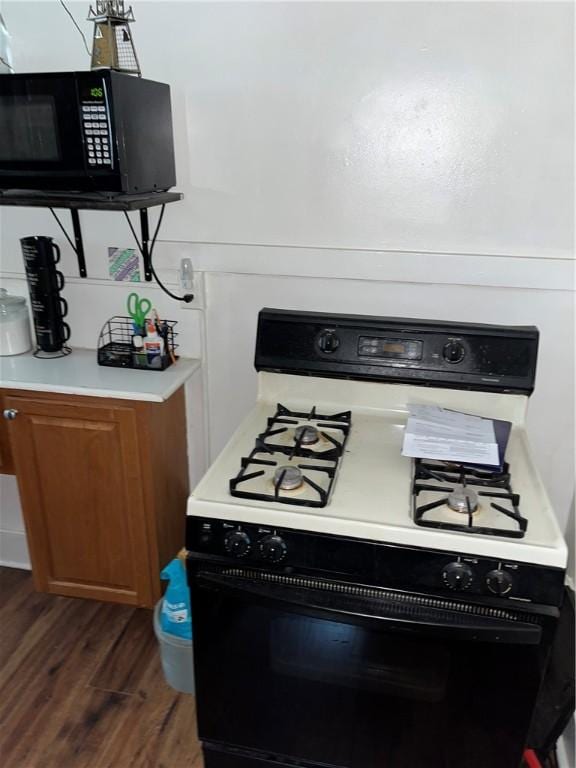 571 Lake Ave, Rochester, NY 14613 - kitchen featuring range with gas cooktop, black microwave, dark wood-style floors, light countertops, and brown cabinets
