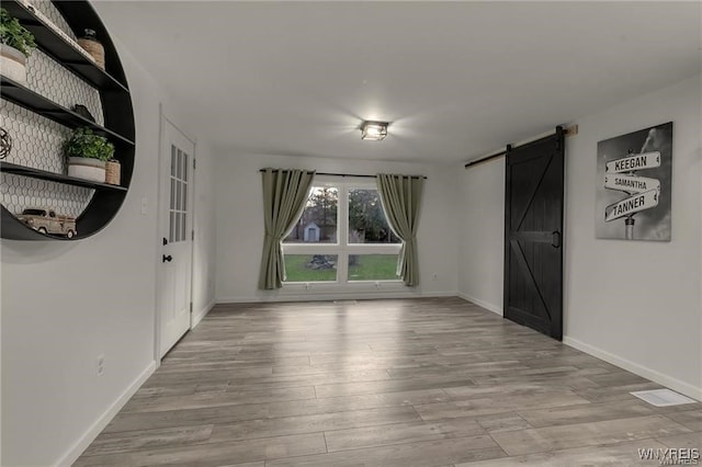 3293 Hartland Rd, Hartland, NY 14067 - empty room with a barn door, wood finished floors, and baseboards