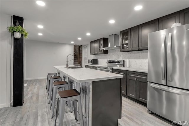 3293 Hartland Rd, Hartland, NY 14067 - kitchen with appliances with stainless steel finishes, a sink, wall chimney range hood, light stone countertops, and an island with sink