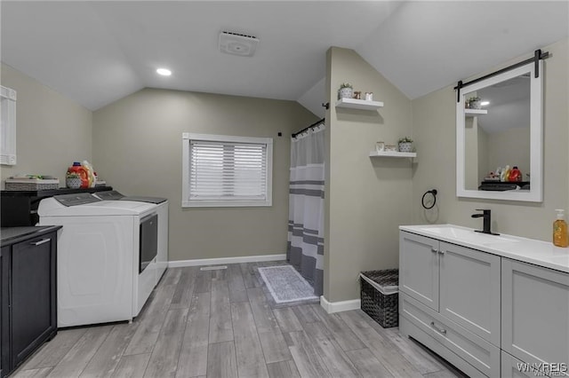 3293 Hartland Rd, Hartland, NY 14067 - laundry area with a sink, washer and dryer, a barn door, light wood-style flooring, and baseboards