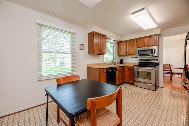 11 Brightwoods Ln, Brighton, NY 14623 - kitchen with appliances with stainless steel finishes, a sink, light countertops, brown cabinetry, and baseboards