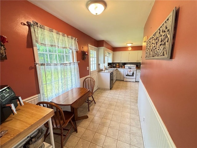 46 Dickerson St, Lyons, NY 14489 - kitchen with white electric stove, dishwasher, wainscoting, light tile patterned floors, and white cabinets