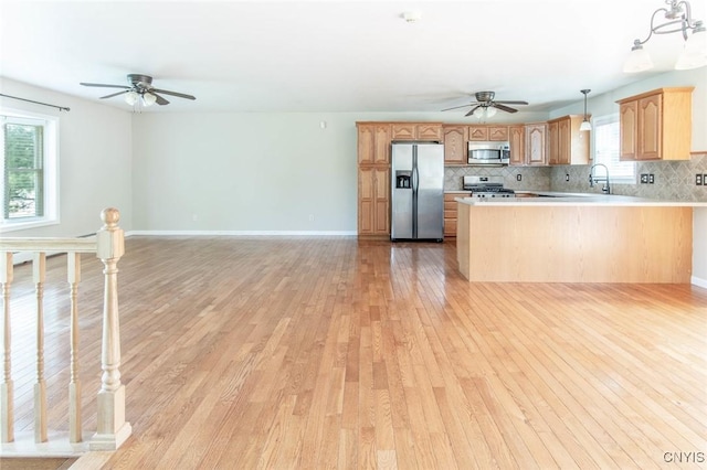 25386 Stewart Dr, Champion, NY 13619 - kitchen with stainless steel appliances, a ceiling fan, light wood finished floors, decorative backsplash, and a peninsula