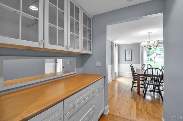 11 S Meadow Dr, Orchard Park, NY 14127 - kitchen featuring glass insert cabinets, light wood-type flooring, a chandelier, light countertops, and pendant lighting