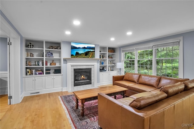 11 S Meadow Dr, Orchard Park, NY 14127 - living area with light wood-style flooring, a tiled fireplace, built in features, recessed lighting, and ornamental molding