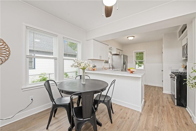 131 Pomona Dr, Greece, NY 14616 - dining area with light wood finished floors, wainscoting, and ceiling fan