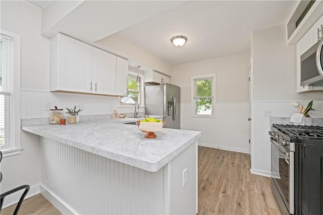 131 Pomona Dr, Greece, NY 14616 - kitchen with appliances with stainless steel finishes, light countertops, wainscoting, light wood-style floors, and white cabinetry