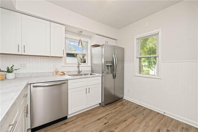 131 Pomona Dr, Greece, NY 14616 - kitchen featuring appliances with stainless steel finishes, a sink, a wainscoted wall, light wood-style flooring, and white cabinetry