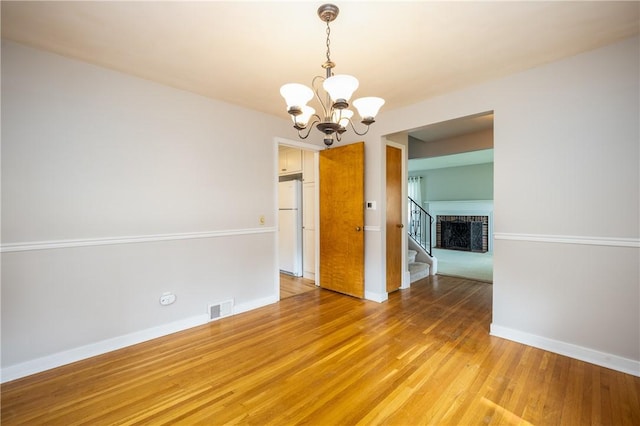 1711 N Winton Rd, Irondequoit, NY 14609 - empty room with a chandelier, stairway, light wood-style flooring, and baseboards