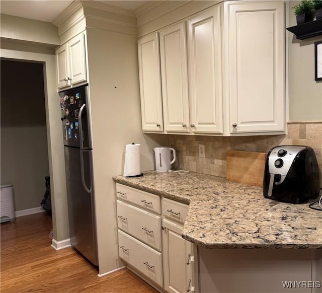 4547 Chestnut Ridge Rd Unit 104B, Amherst, NY 14228 - kitchen with freestanding refrigerator, light wood-type flooring, white cabinets, tasteful backsplash, and baseboards