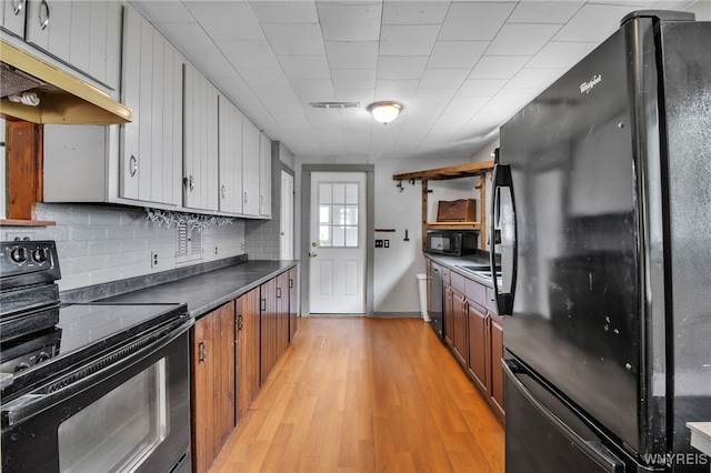 6305 E Main St, Byron, NY 14557 - kitchen featuring black appliances, under cabinet range hood, backsplash, dark countertops, and light wood-type flooring