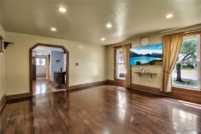 6305 E Main St, Byron, NY 14557 - spare room featuring arched walkways, dark wood-style flooring, recessed lighting, baseboards, and a wood stove