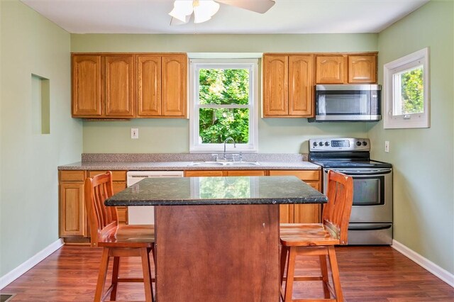 86 Leonard Rd, Greece, NY 14616 - kitchen featuring appliances with stainless steel finishes, a sink, a kitchen breakfast bar, dark wood-style flooring, and healthy amount of natural light