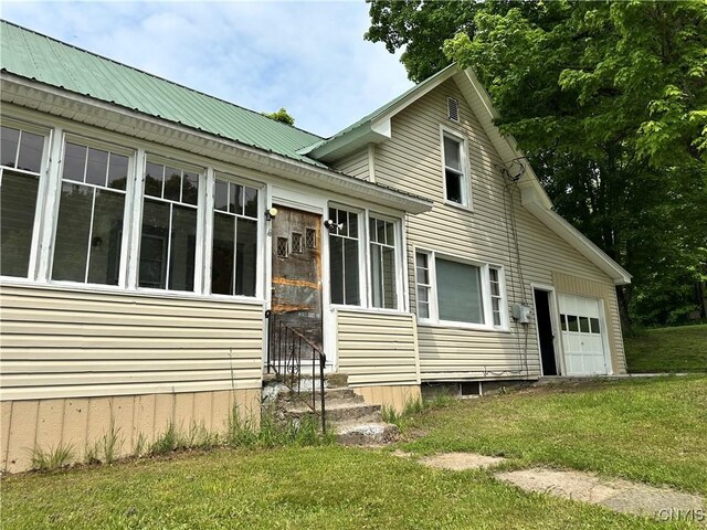 21 Church St, Fine, NY 13617 - view of side of property featuring entry steps, a lawn, an attached garage, and metal roof