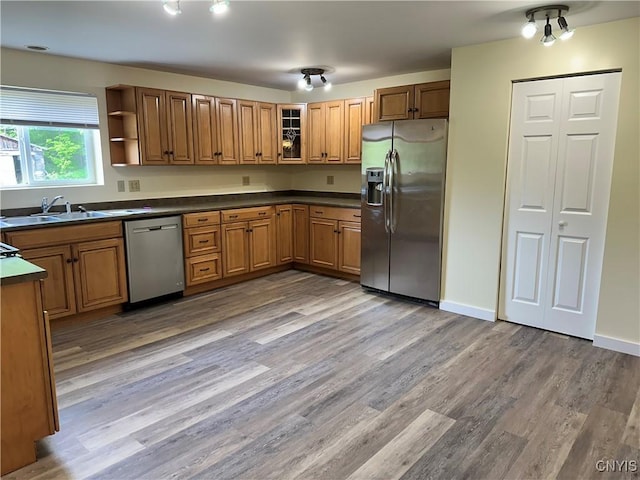 21 Church St, Fine, NY 13617 - kitchen with stainless steel appliances, brown cabinets, a sink, light wood-type flooring, and dark countertops