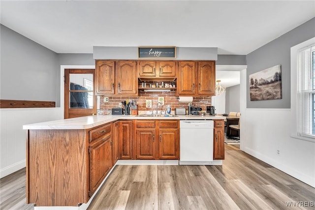 355 Bryant St, North Tonawanda, NY 14120 - kitchen featuring dishwasher, a sink, light wood finished floors, a peninsula, and brown cabinetry