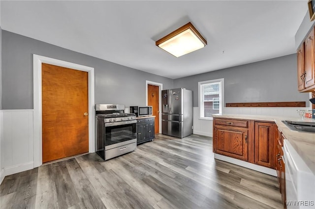 355 Bryant St, North Tonawanda, NY 14120 - kitchen with stainless steel appliances, light countertops, a wainscoted wall, light wood-style flooring, and a sink