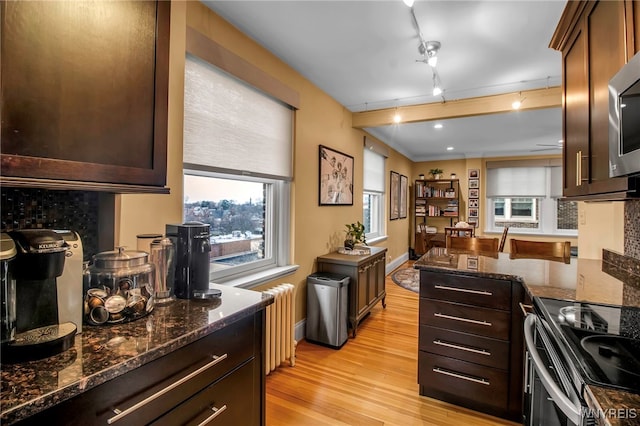 83 Bryant St Unit 7D, Buffalo, NY 14209 - kitchen with radiator, light wood finished floors, dark stone countertops, and dark brown cabinetry