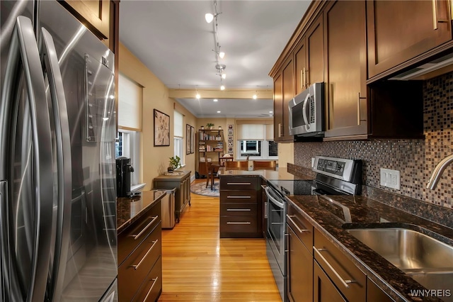 83 Bryant St Unit 7D, Buffalo, NY 14209 - kitchen featuring appliances with stainless steel finishes, a sink, light wood-style flooring, decorative backsplash, and dark stone countertops