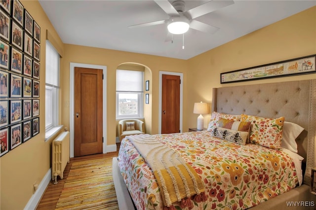 83 Bryant St Unit 7D, Buffalo, NY 14209 - bedroom featuring radiator, arched walkways, baseboards, and wood finished floors