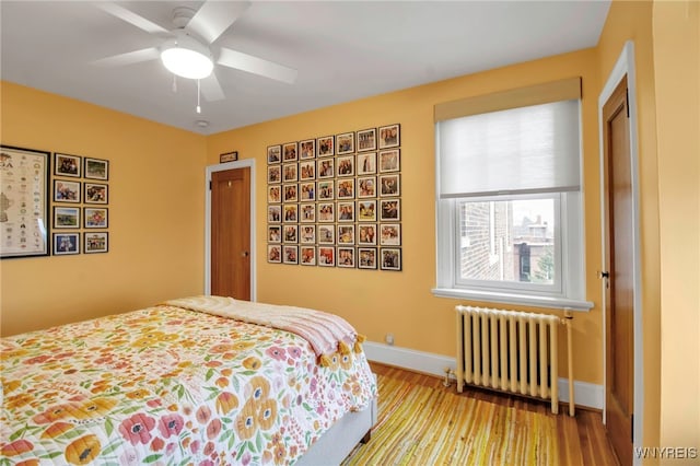 83 Bryant St Unit 7D, Buffalo, NY 14209 - bedroom featuring radiator, wood finished floors, baseboards, and a ceiling fan