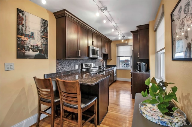 83 Bryant St Unit 7D, Buffalo, NY 14209 - kitchen featuring appliances with stainless steel finishes, dark brown cabinetry, a sink, tasteful backsplash, and a peninsula