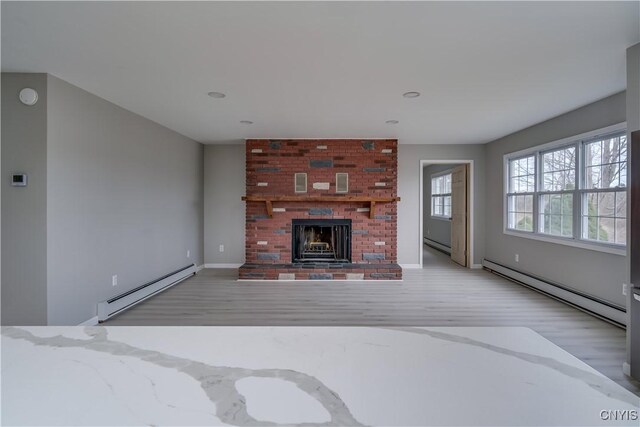 34292 State Route 26, Champion, NY 13619 - unfurnished living room featuring a baseboard radiator, light wood-style flooring, and a fireplace