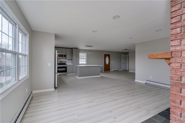 34292 State Route 26, Champion, NY 13619 - unfurnished living room featuring a baseboard heating unit, light wood finished floors, and baseboards