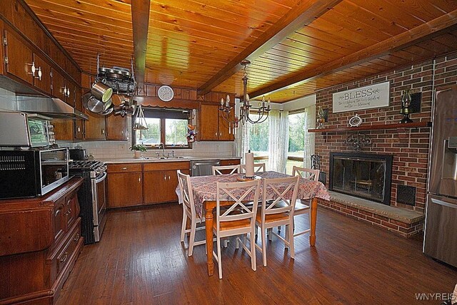 2477 Ridge Rd, Lewiston, NY 14131 - dining room featuring healthy amount of natural light, dark wood finished floors, a chandelier, wood ceiling with exposed beams, and a brick fireplace