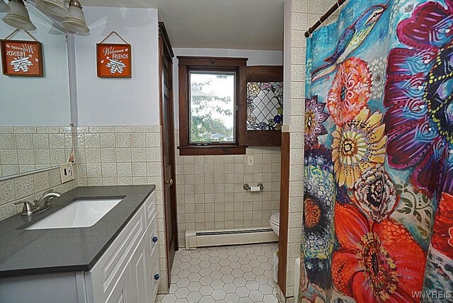 2477 Ridge Rd, Lewiston, NY 14131 - full bath with a baseboard heating unit, tile walls, vanity, toilet, and tile patterned floors
