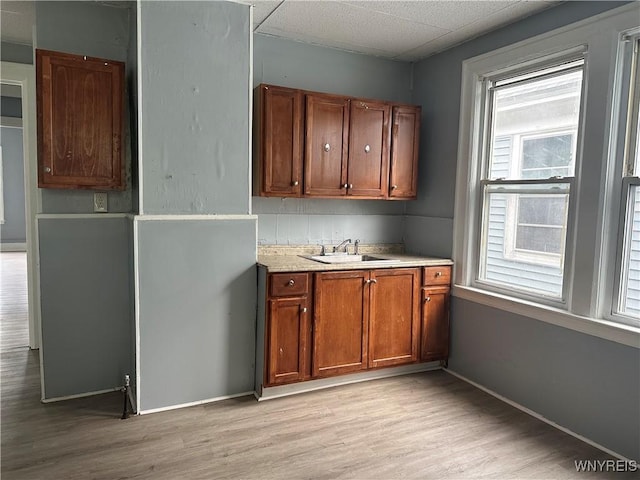 64 Barton St, Buffalo, NY 14213 - kitchen with a sink, light wood-style floors, light countertops, brown cabinetry, and a drop ceiling
