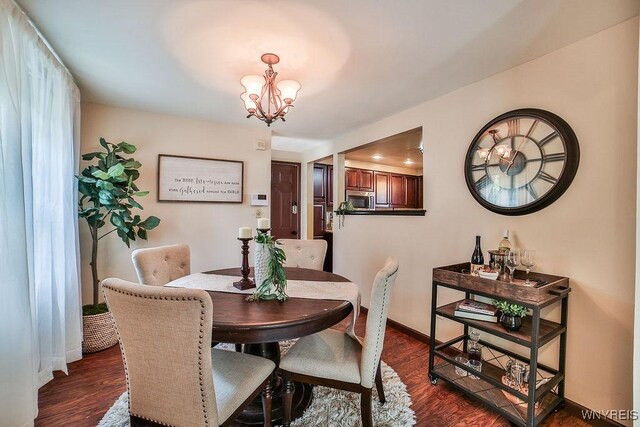 305 Vine Ln, Amherst, NY 14228 - dining area featuring a chandelier, dark wood-type flooring, and baseboards