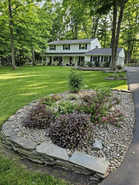 52 Woodland Dr, Big Flats, NY 14814 - view of front facade featuring a front lawn, covered porch, a chimney, and view of wooded area