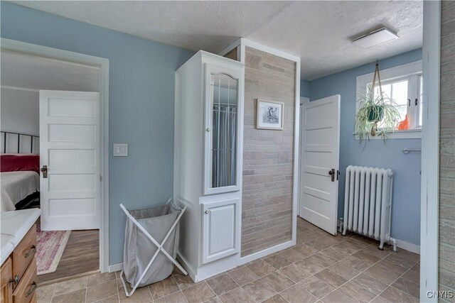 621 N Hycliff Dr, Watertown-City, NY 13601 - bathroom with radiator heating unit, vanity, baseboards, a textured ceiling, and ensuite bath