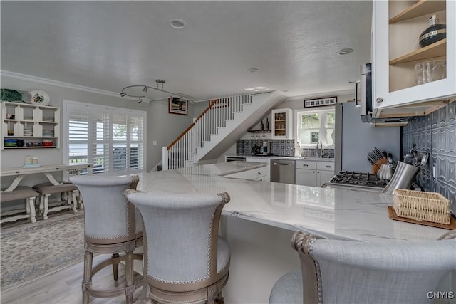 32160 State Route 12e, Cape Vincent, NY 13618 - kitchen with appliances with stainless steel finishes, light stone counters, a sink, tasteful backsplash, and a kitchen breakfast bar