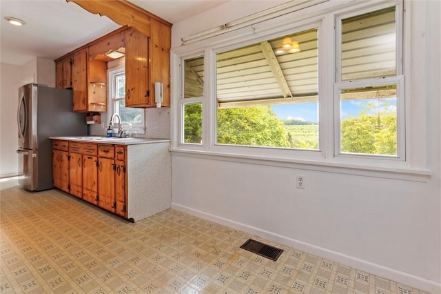 4411 Williamson Rd, Marion, NY 14505 - kitchen with a sink, baseboards, light countertops, freestanding refrigerator, and brown cabinetry