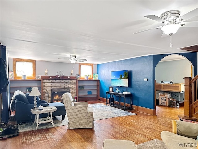 4 Park Rd W, Castile, NY 14427 - living room featuring a ceiling fan, wood finished floors, baseboards, a brick fireplace, and arched walkways