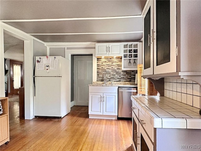 4 Park Rd W, Castile, NY 14427 - kitchen featuring freestanding refrigerator, stainless steel dishwasher, tile countertops, light wood-style flooring, and backsplash