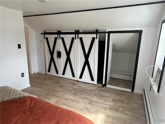 808 Fay, Bangor, NY 12966 - bedroom featuring a baseboard heating unit, lofted ceiling, wood finished floors, baseboards, and a barn door