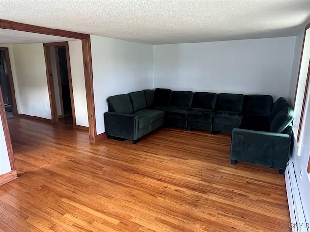 808 Fay, Bangor, NY 12966 - unfurnished living room featuring light wood finished floors, a textured ceiling, a baseboard radiator, and baseboards