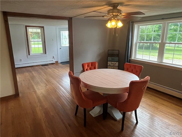 808 Fay, Bangor, NY 12966 - dining room with a baseboard heating unit, hardwood / wood-style flooring, healthy amount of natural light, and a textured ceiling