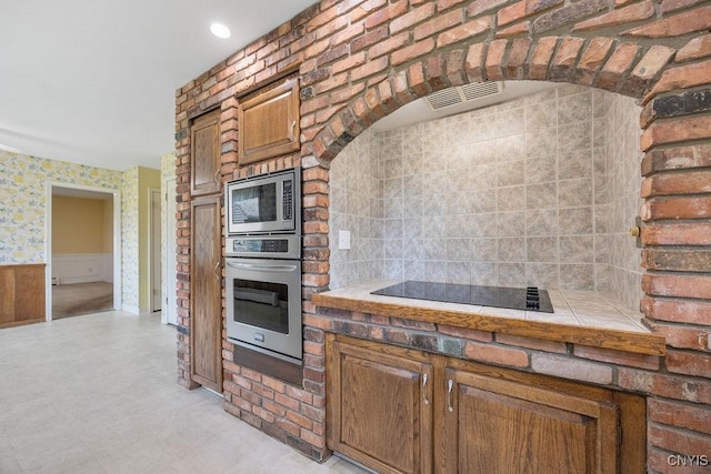 7739 Number 5 W Rd, Pompey, NY 13063 - kitchen with stainless steel appliances, wainscoting, brown cabinetry, tile countertops, and light floors