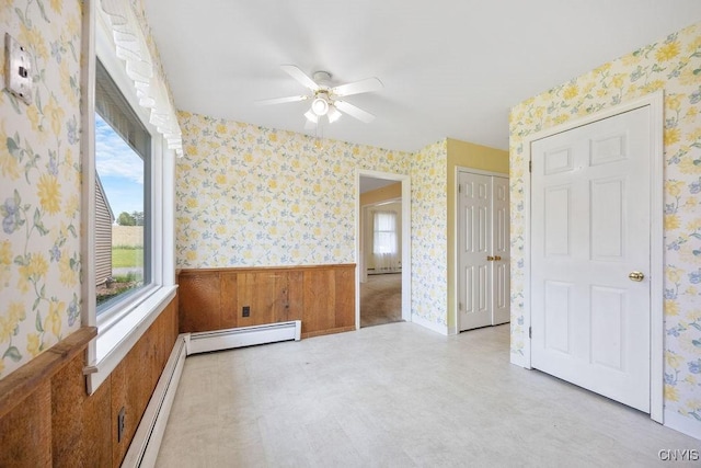 7739 Number 5 W Rd, Pompey, NY 13063 - empty room featuring a baseboard radiator, a ceiling fan, wallpapered walls, tile patterned floors, and wainscoting