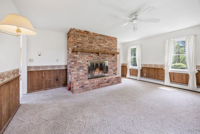 7739 Number 5 W Rd, Pompey, NY 13063 - unfurnished living room with wainscoting, a ceiling fan, a fireplace, wooden walls, and a baseboard heating unit
