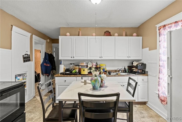 417 18th St, Niagara Falls, NY 14303 - kitchen with freestanding refrigerator, white cabinets, a sink, a textured ceiling, and electric range