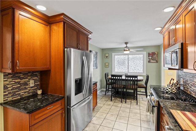 193 Floral Dr, Irondequoit, NY 14617 - kitchen featuring appliances with stainless steel finishes, decorative backsplash, light tile patterned flooring, a ceiling fan, and dark stone countertops