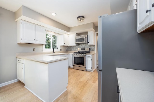 6 Barben Cir, Mendon, NY 14506 - kitchen with appliances with stainless steel finishes, light wood finished floors, white cabinetry, a peninsula, and light countertops