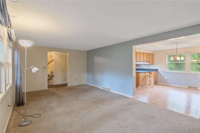 3643 Armstrong Rd, Camillus, NY 13209 - unfurnished living room featuring light colored carpet, stairs, baseboards, and a chandelier