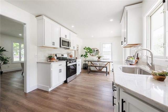 3908 Stalker Rd, Walworth, NY 14502 - kitchen featuring stainless steel appliances, a sink, wood finished floors, white cabinetry, and tasteful backsplash