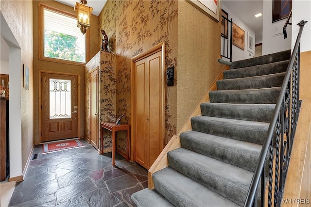 9325 Hunting Valley Rd N, Clarence, NY 14031 - foyer with healthy amount of natural light, stone tile flooring, stairs, and wallpapered walls